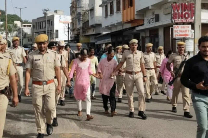 The accused murderers were paraded in the market dressed in women’s clothes, a crowd gathered to watch.